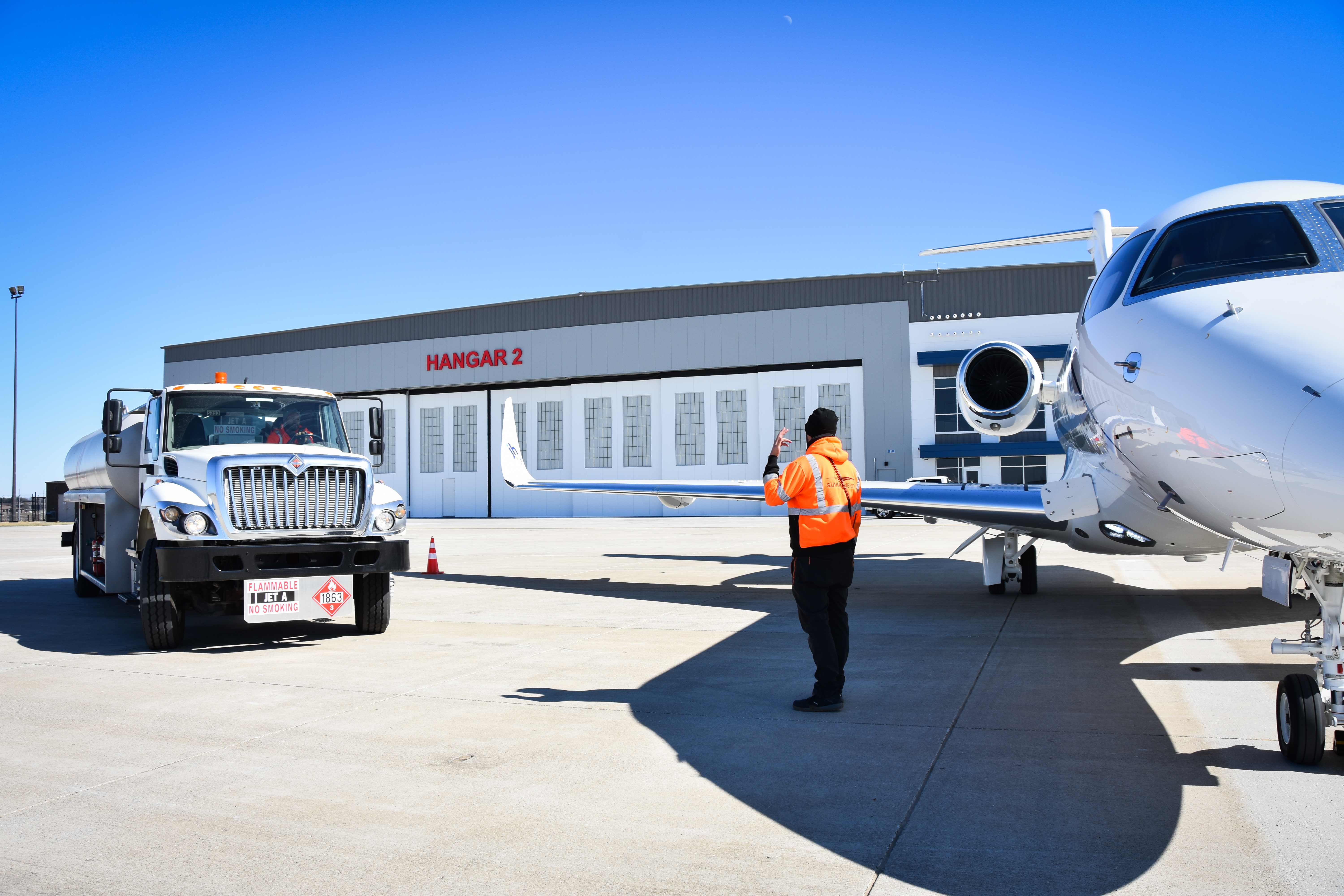 Gasoline truck and plane in front of hangar
